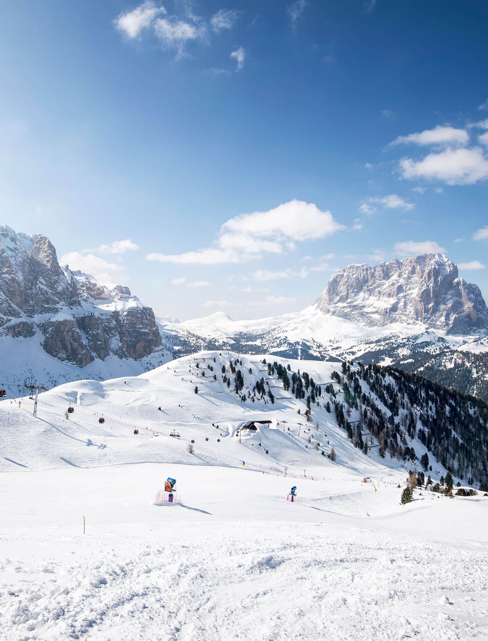 Verschneite Berglandschaft mit Skifahrern, Kiefern und blauem Himmel mit vereinzelten Wolken. - Hotel Kristiania