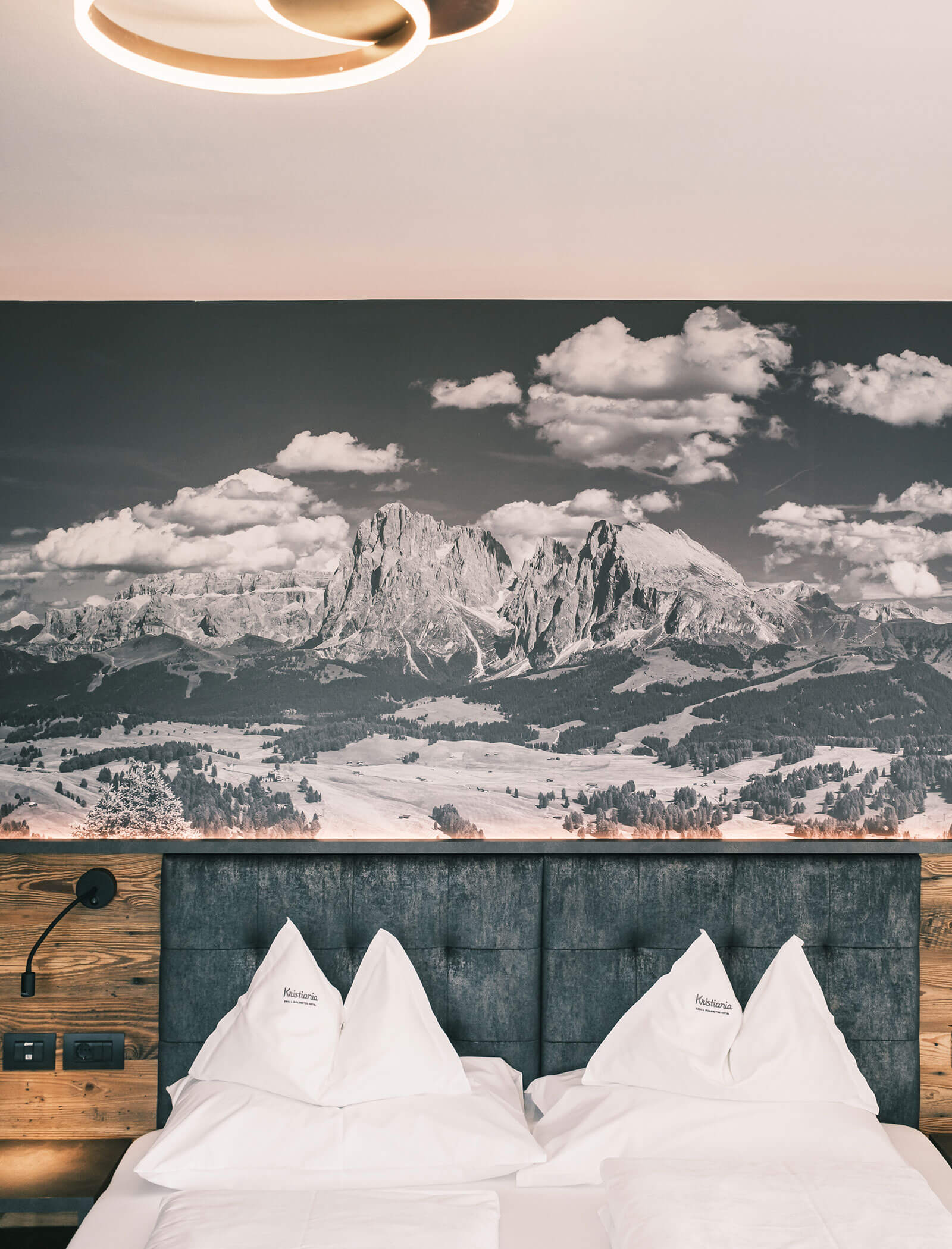Modernes Hotelzimmer mit einem Doppelbett und einem großen Bergbild an der Wand hinter dem Kopfteil. - Hotel Kristiania