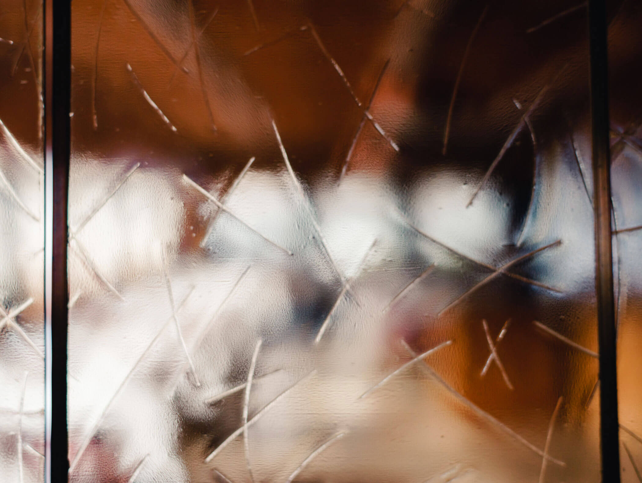 Blurry textured glass with random scratched lines, light and brown colors visible through the glass. - Hotel Kristiania
