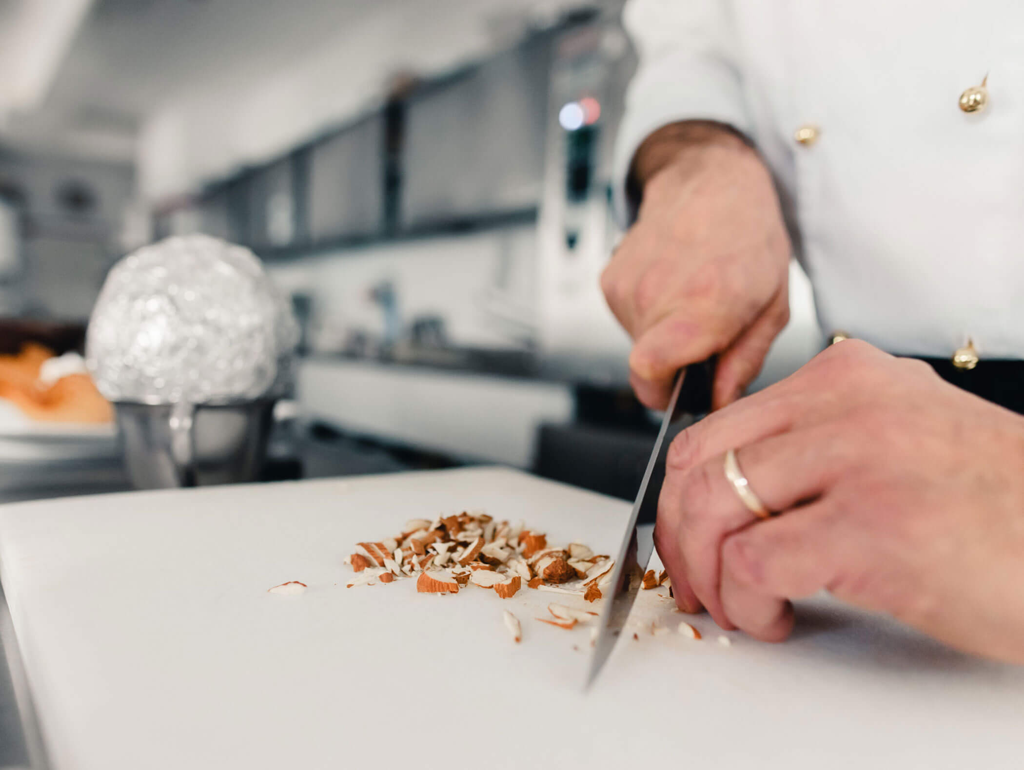 Close-up of a chef chopping mushrooms on a white cutting board in a kitchen. - Hotel Kristiania