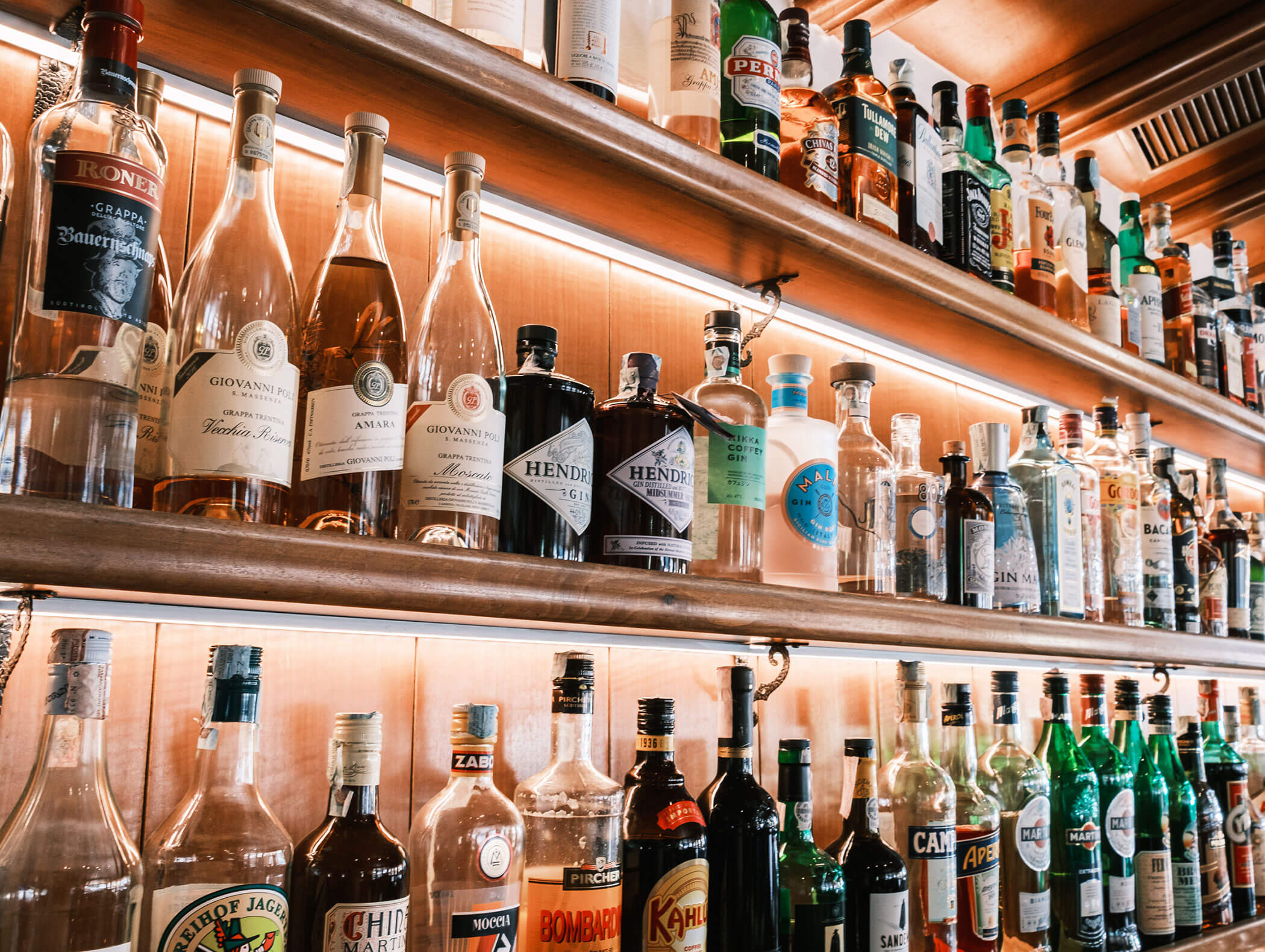 Shelves filled with various liquor bottles arranged in rows at a bar. - Hotel Kristiania