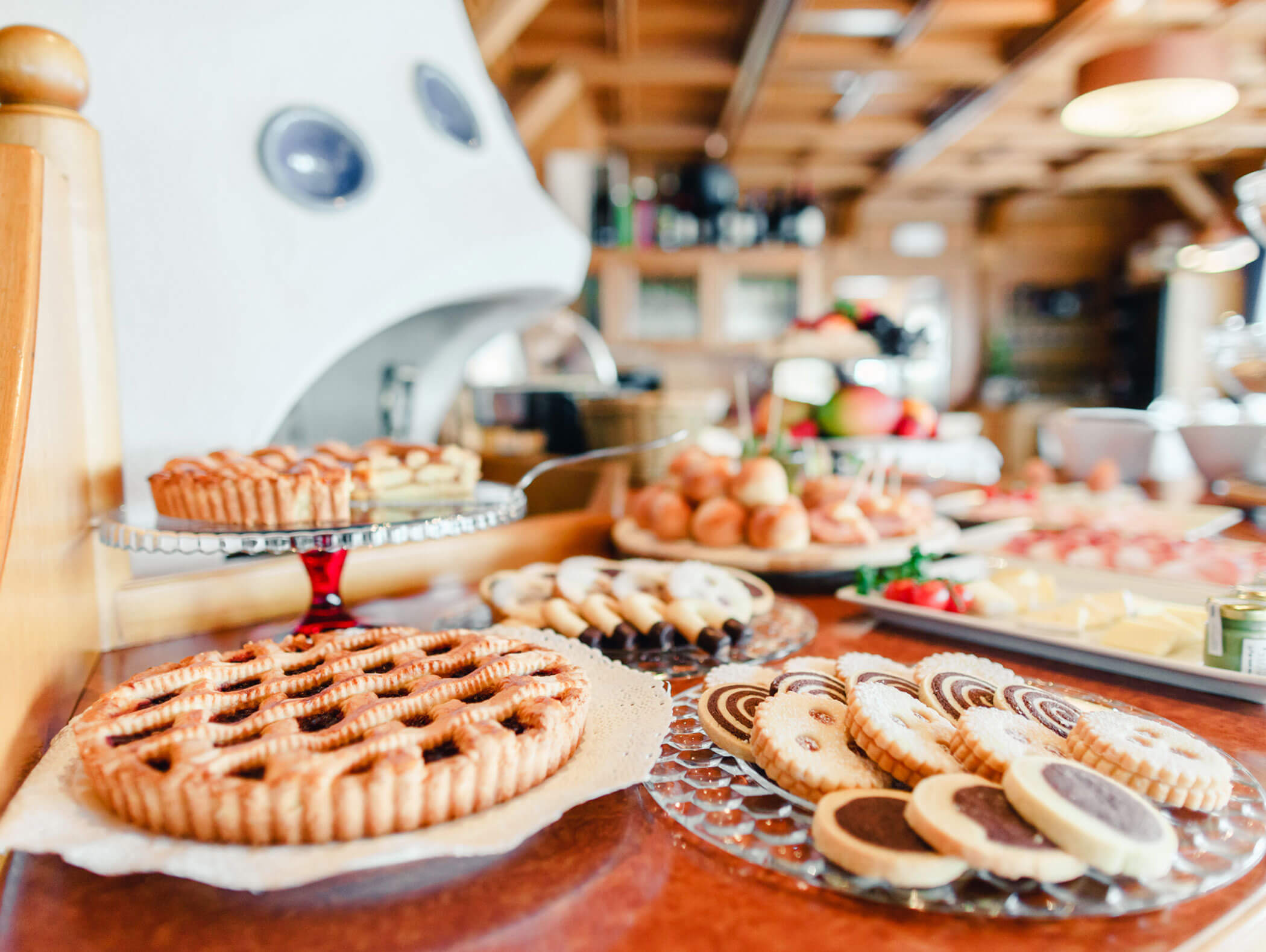 Assorted cookies and fruit tarts displayed on plates in a cozy, rustic bakery setting. - Hotel Kristiania