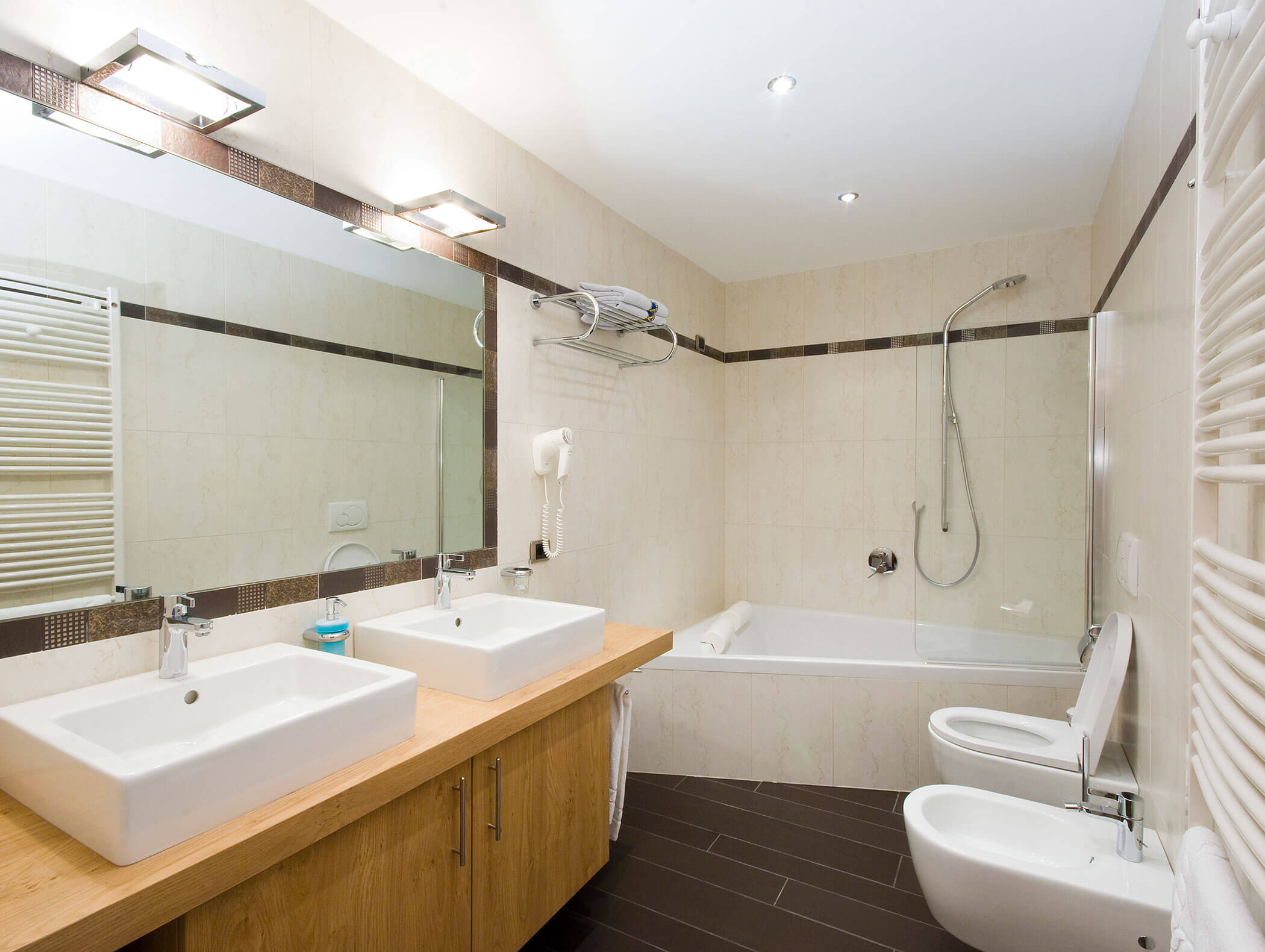 Bagno moderno con doppio lavabo, vasca da bagno con doccia, WC, bidet e ampio specchio a parete. - Hotel Kristiania