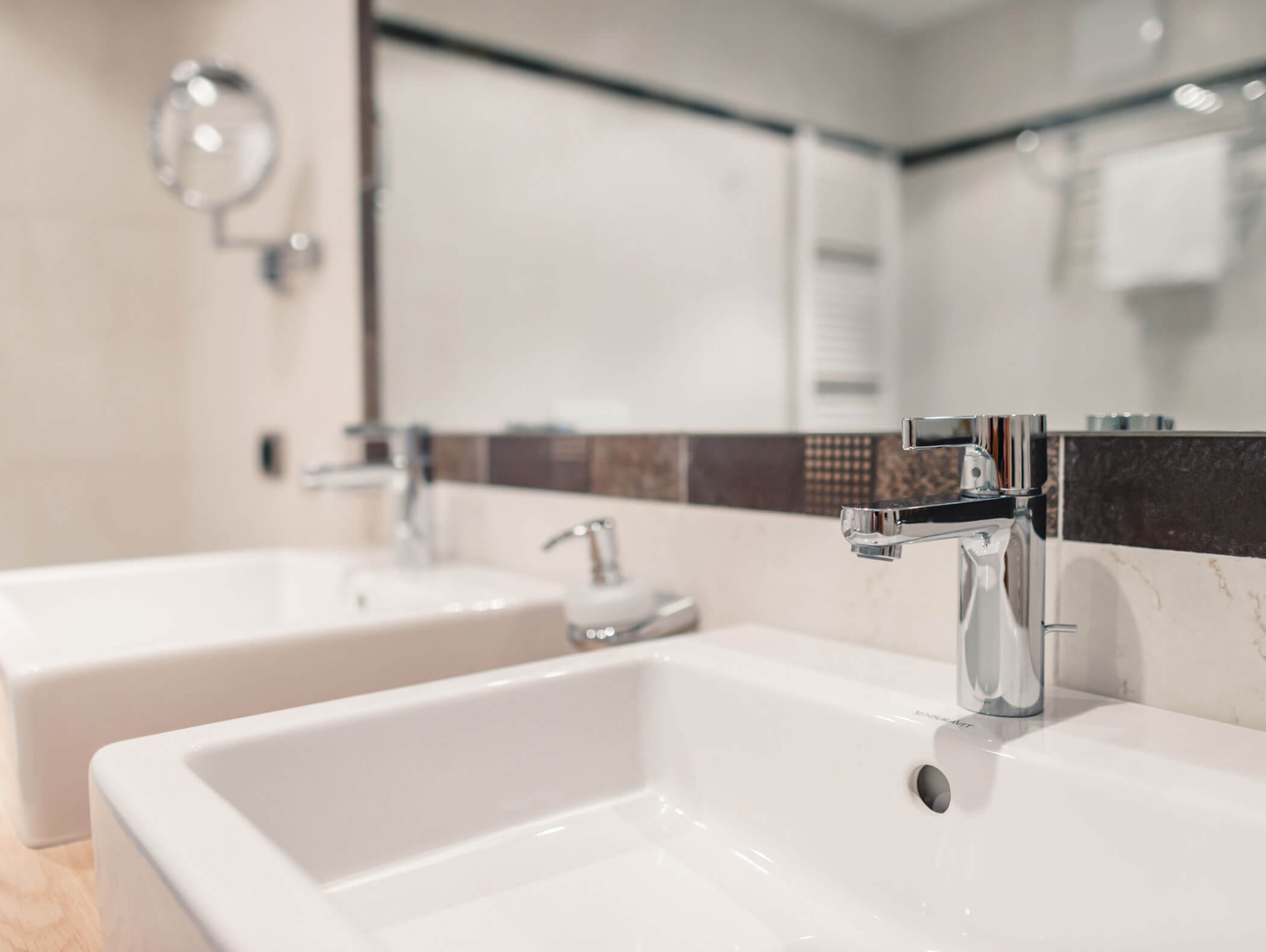 Due moderni lavandini bianchi con rubinetti cromati in un bagno dalle linee pulite e contemporanee. - Hotel Kristiania