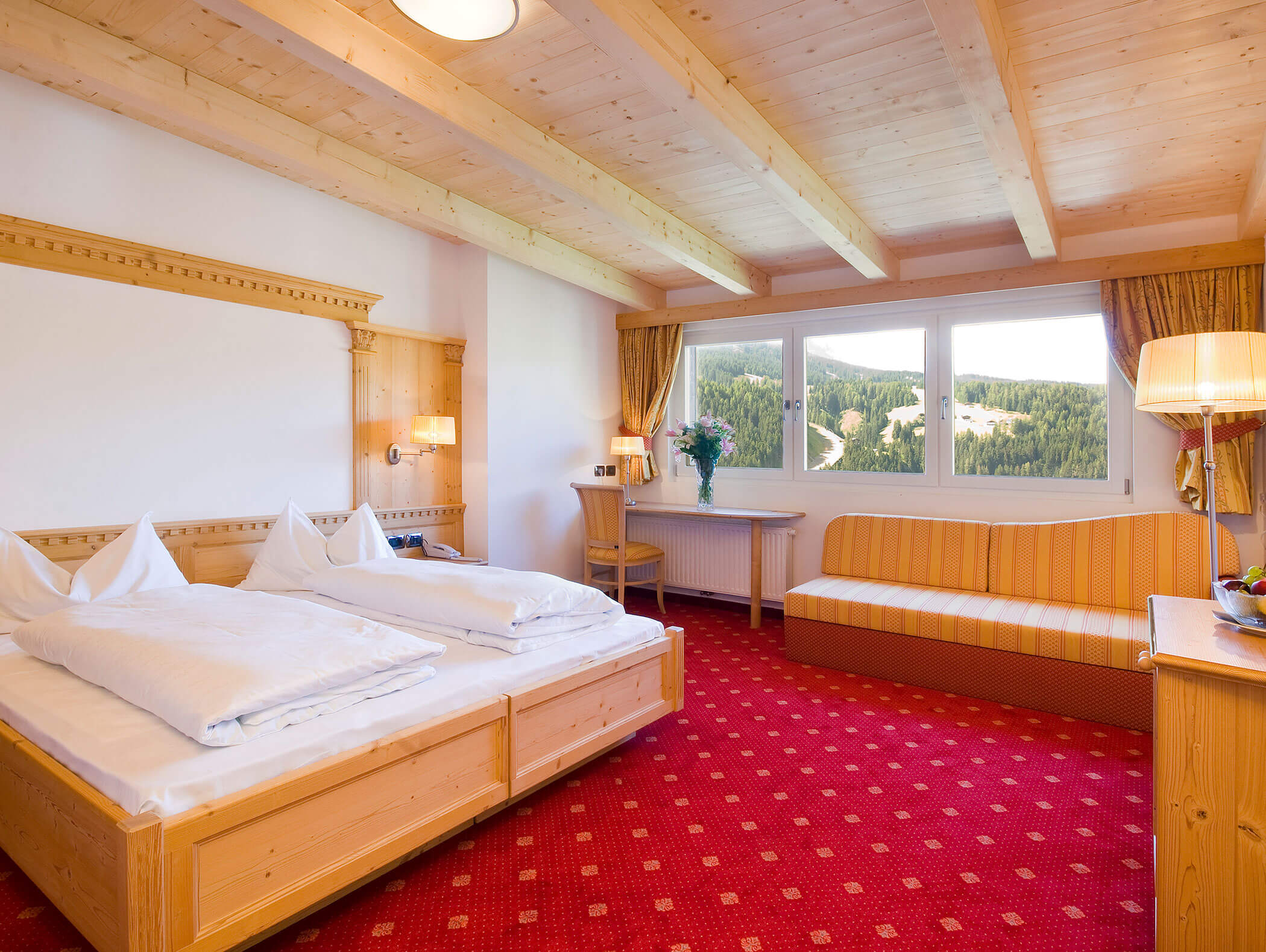 Camera d'albergo con due letti singoli, moquette rossa, mobili in legno, divano, scrivania e un'ampia finestra con vista panoramica. - Hotel Kristiania