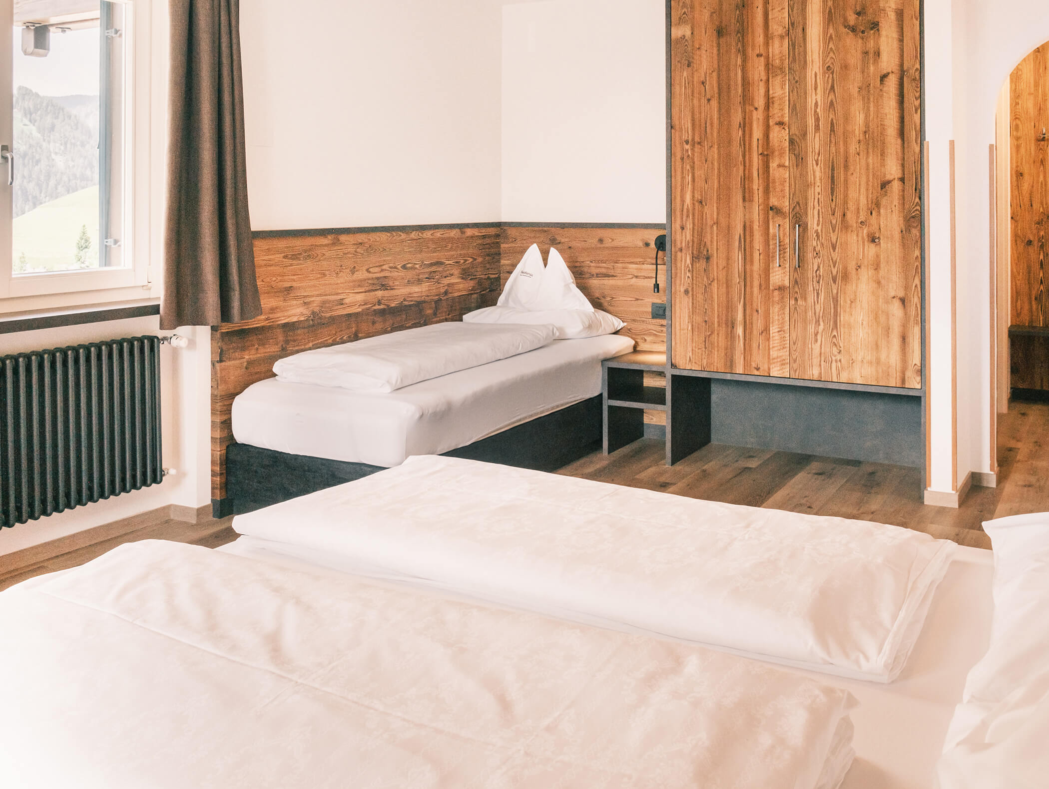 Camera d'albergo luminosa e accogliente, con pareti in legno, due letti, una finestra con tende e luce naturale. - Hotel Kristiania