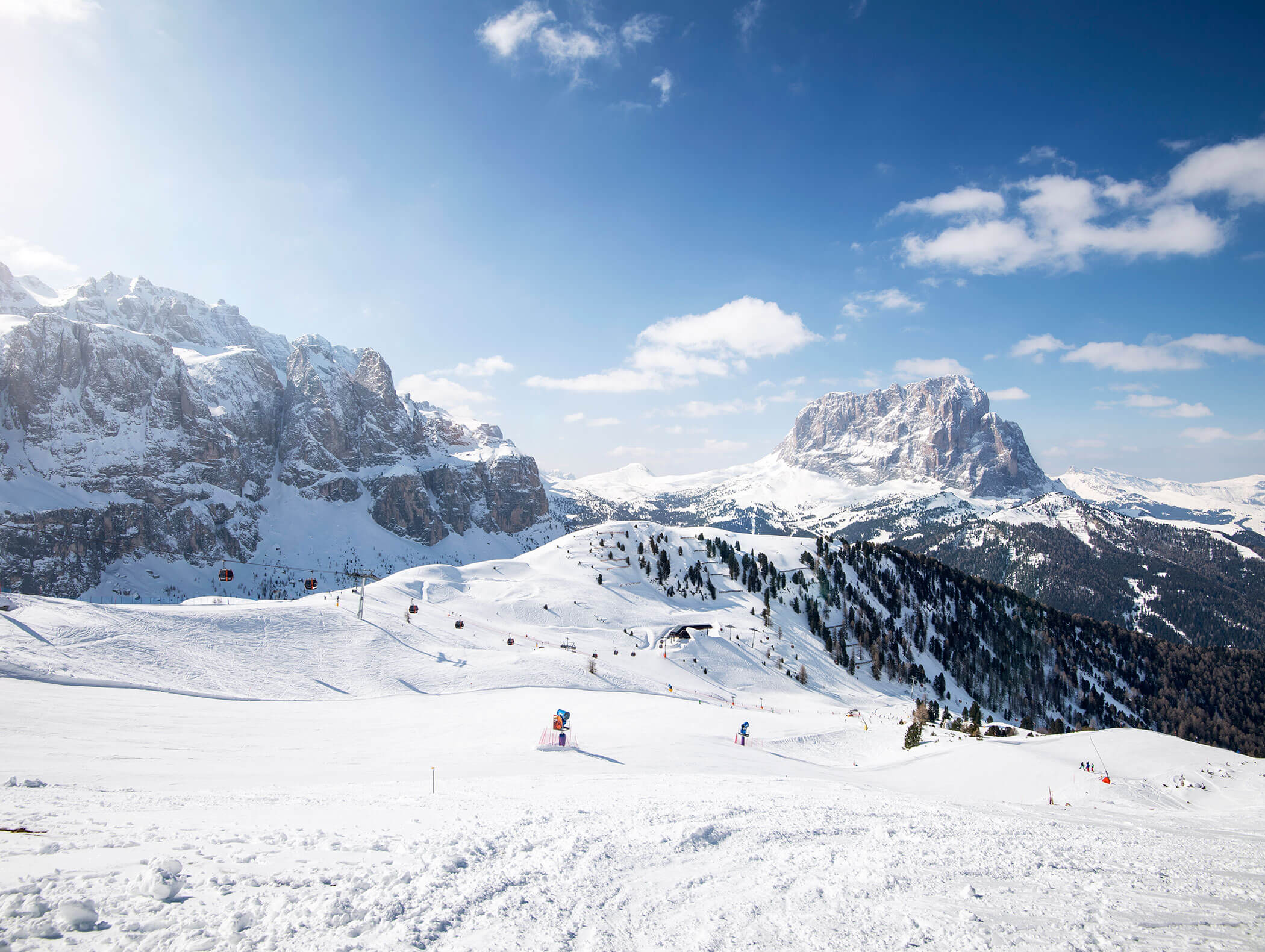 Schneebedeckte Berge und Skipisten unter einem blauen Himmel mit vereinzelten Wolken und Skifahrern in der Ferne. - Hotel Kristiania