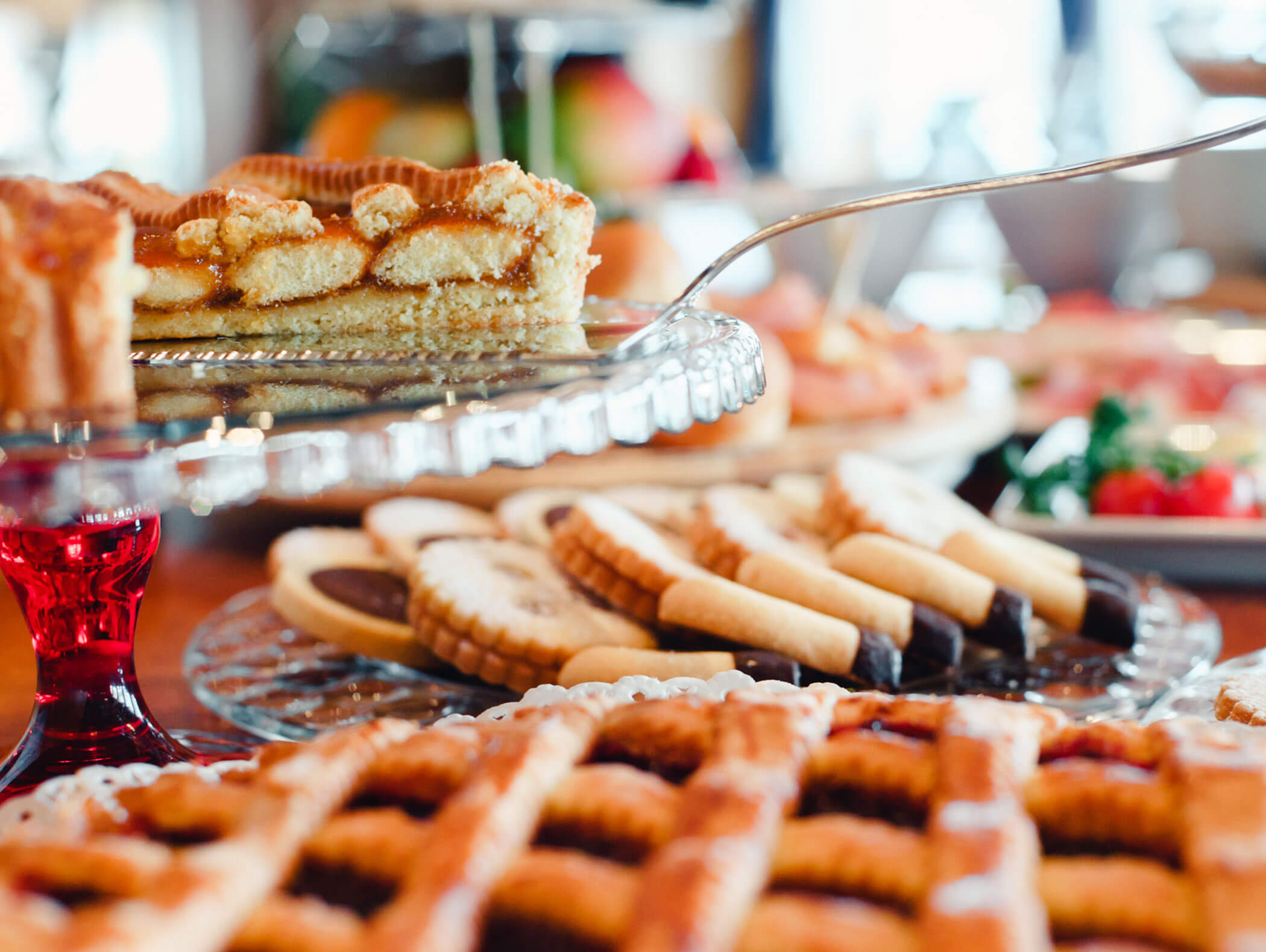 Verschiedene Kekse, Kuchen und Schichttorten, die auf Glastellern an einem Desserttisch präsentiert werden. - Hotel Kristiania