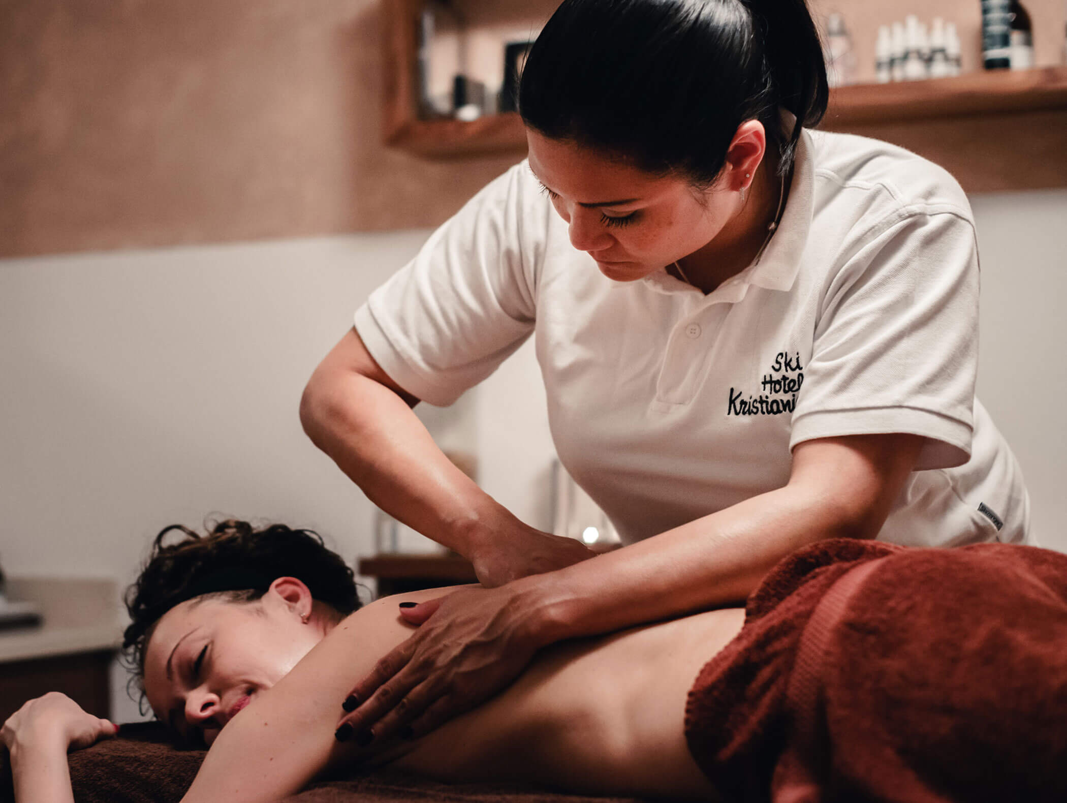 Eine Frau lässt sich von einem Therapeuten in einem Wellnessbereich den Rücken massieren und wirkt dabei entspannt und wohl. - Hotel Kristiania