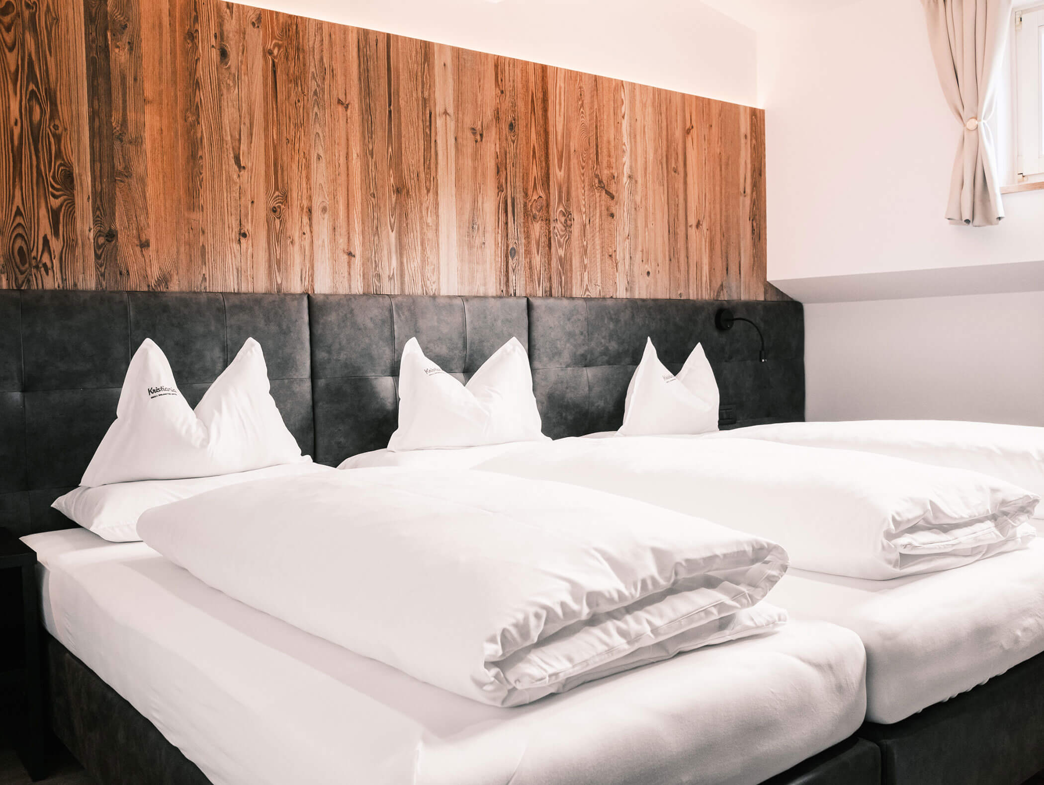 Due letti singoli ben rifatti, con biancheria da letto bianca e testiera in pannelli di legno, in una camera luminosa e moderna. - Hotel Kristiania