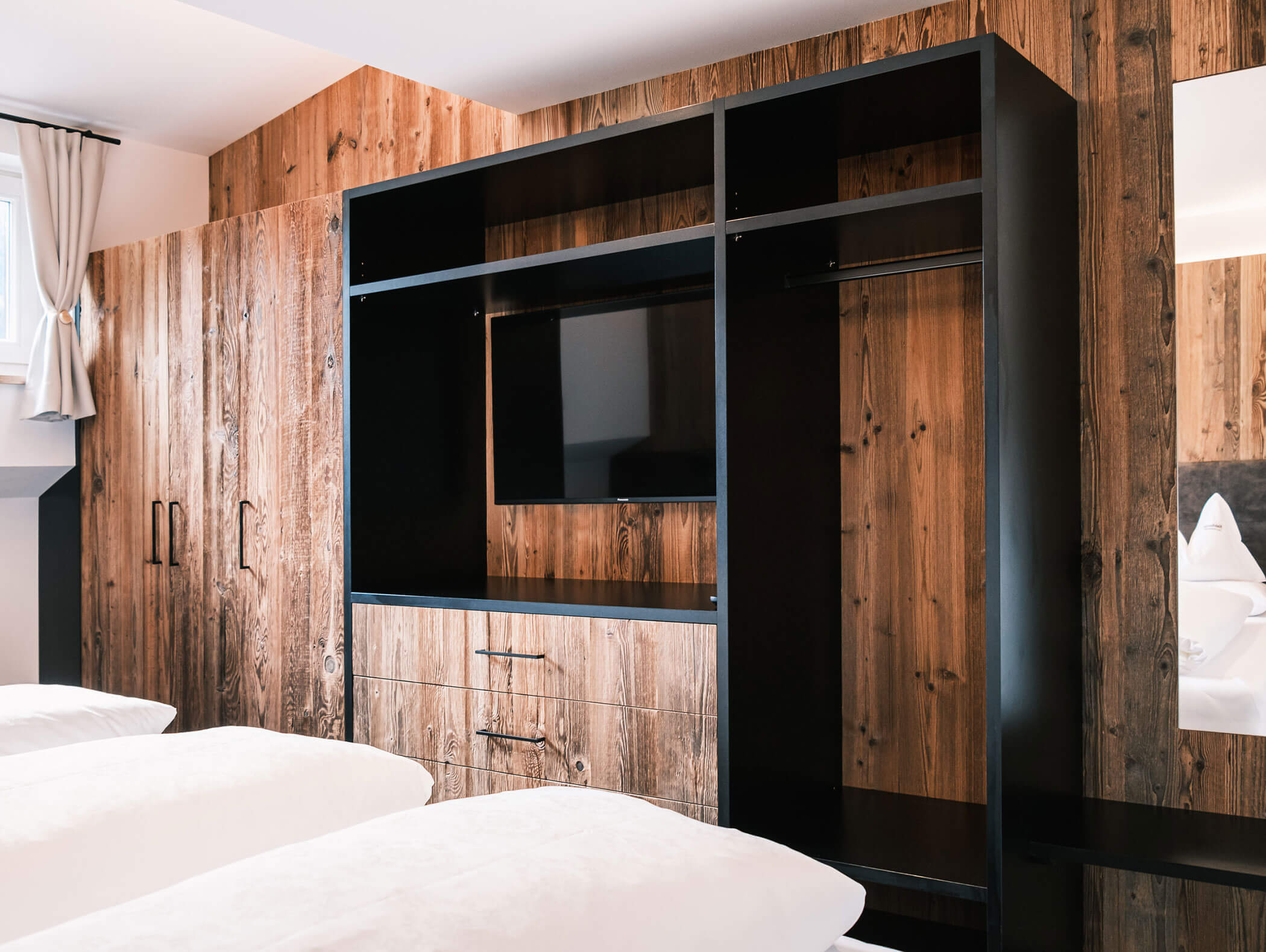 Camera d'albergo moderna con pareti in legno, armadio a vista, TV e letti ben rifatti in primo piano. - Hotel Kristiania