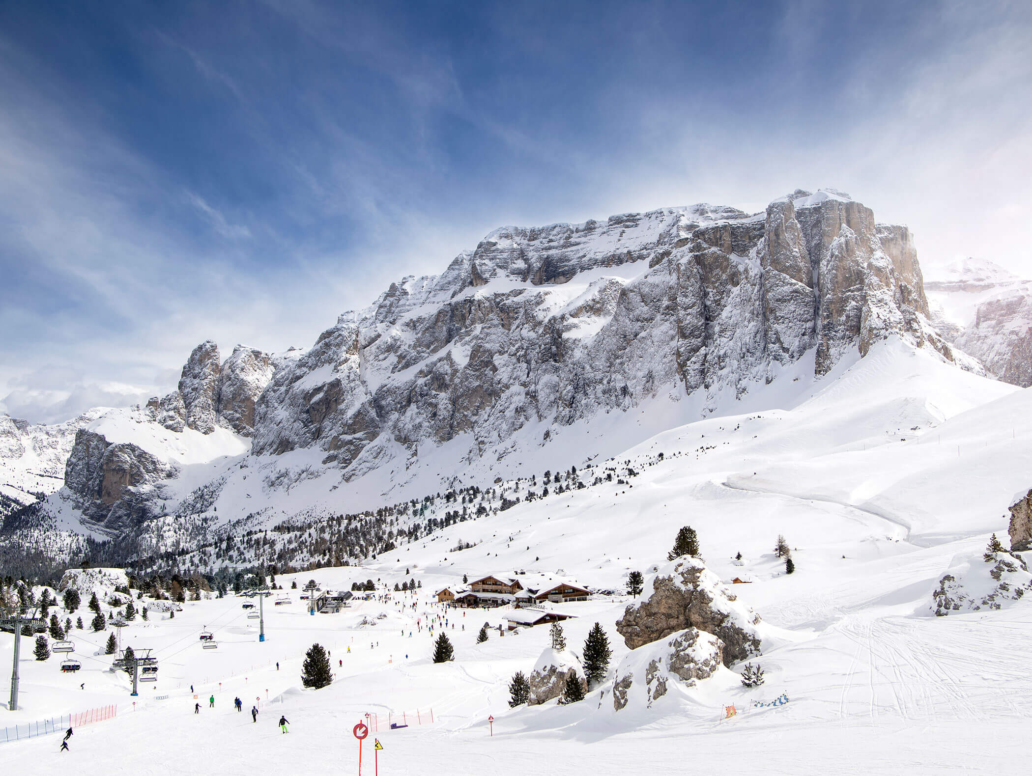 Montagne innevate con sciatori e piccoli edifici ai piedi delle montagne, sotto un cielo parzialmente nuvoloso. - Hotel Kristiania
